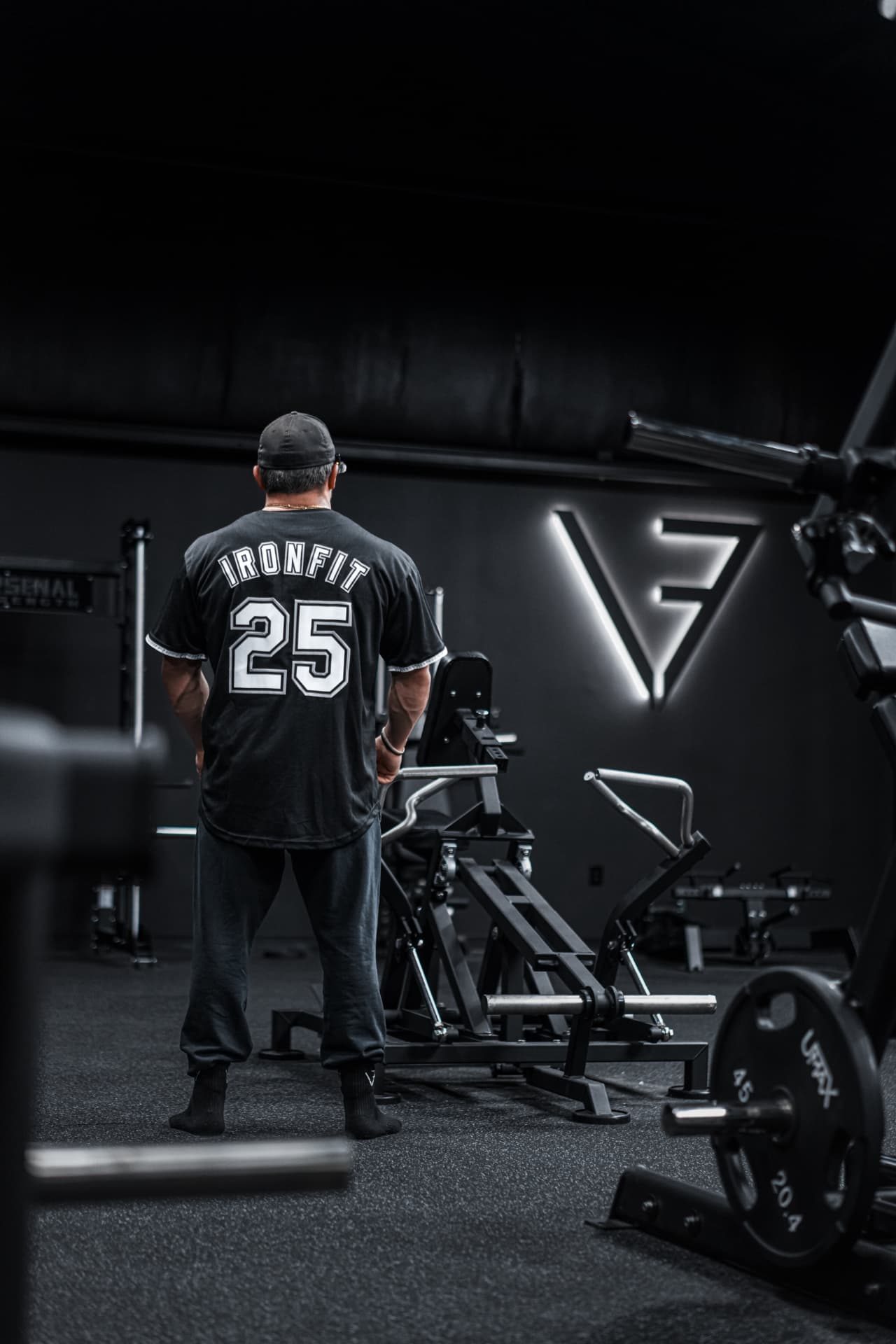 Patrick in his IronFit 25 jersey facing the lit IronFit wall